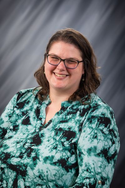 Woman smiling in green shirt with brown curly hair