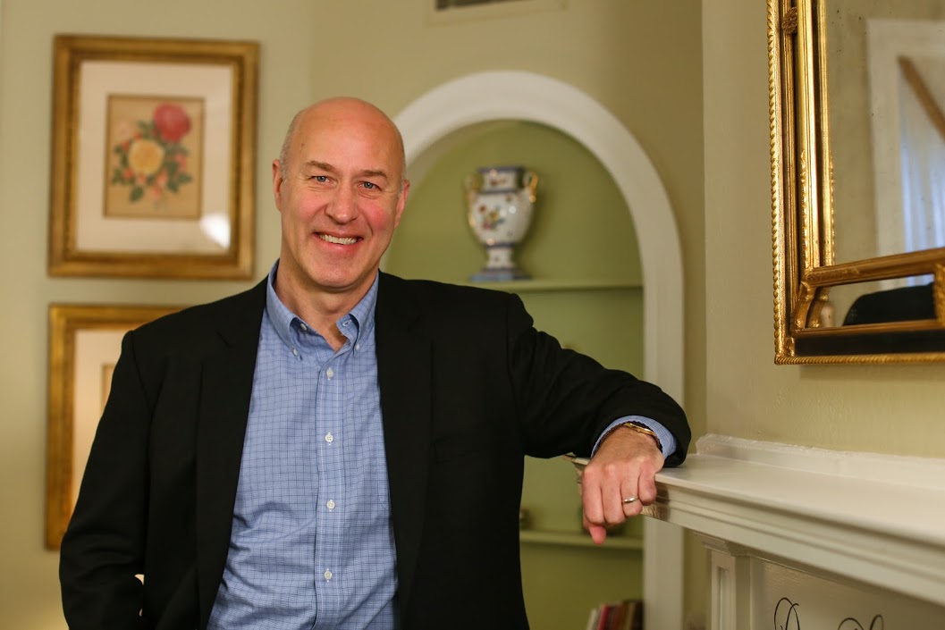 Paul Hanstedt smiles for the camera and leans on a mantelpiece.
